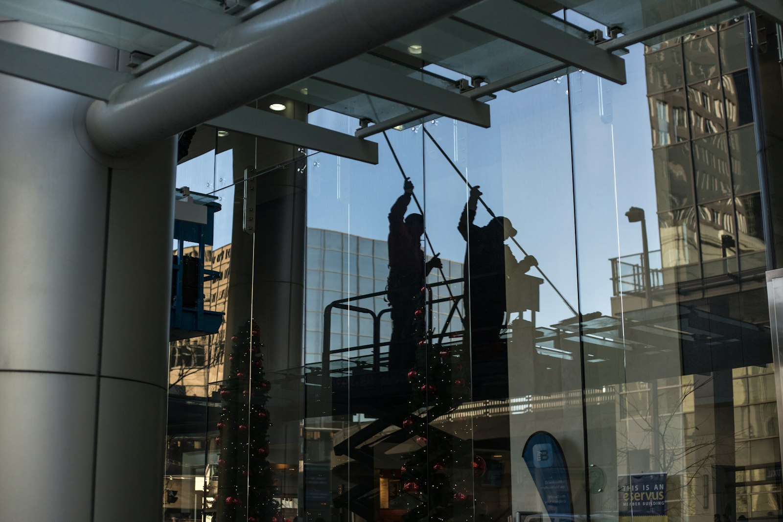 Technician on a scissor lift cleaning large glass windows