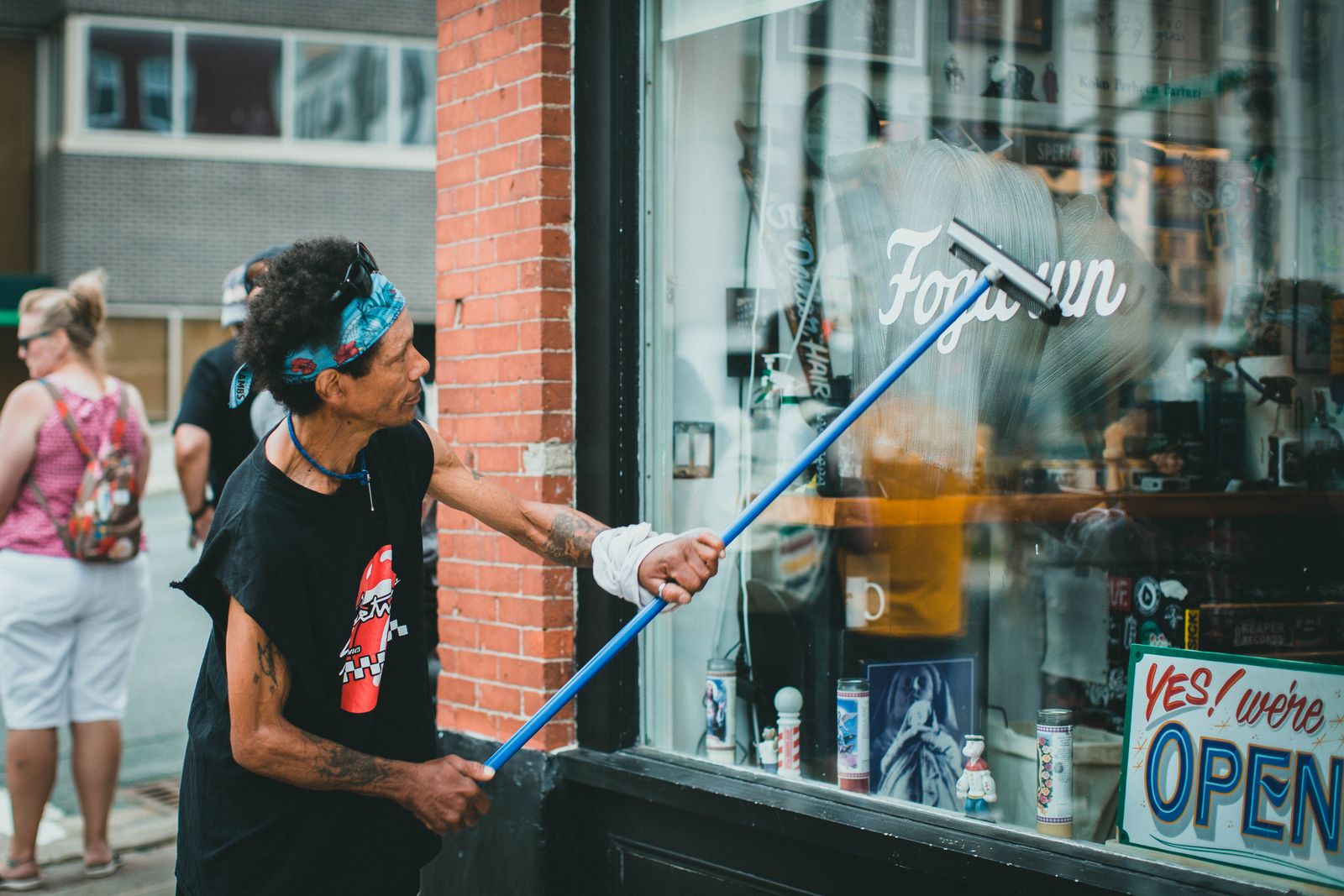 Technician cleaning a shopfront window with a squeegee on an extension pole