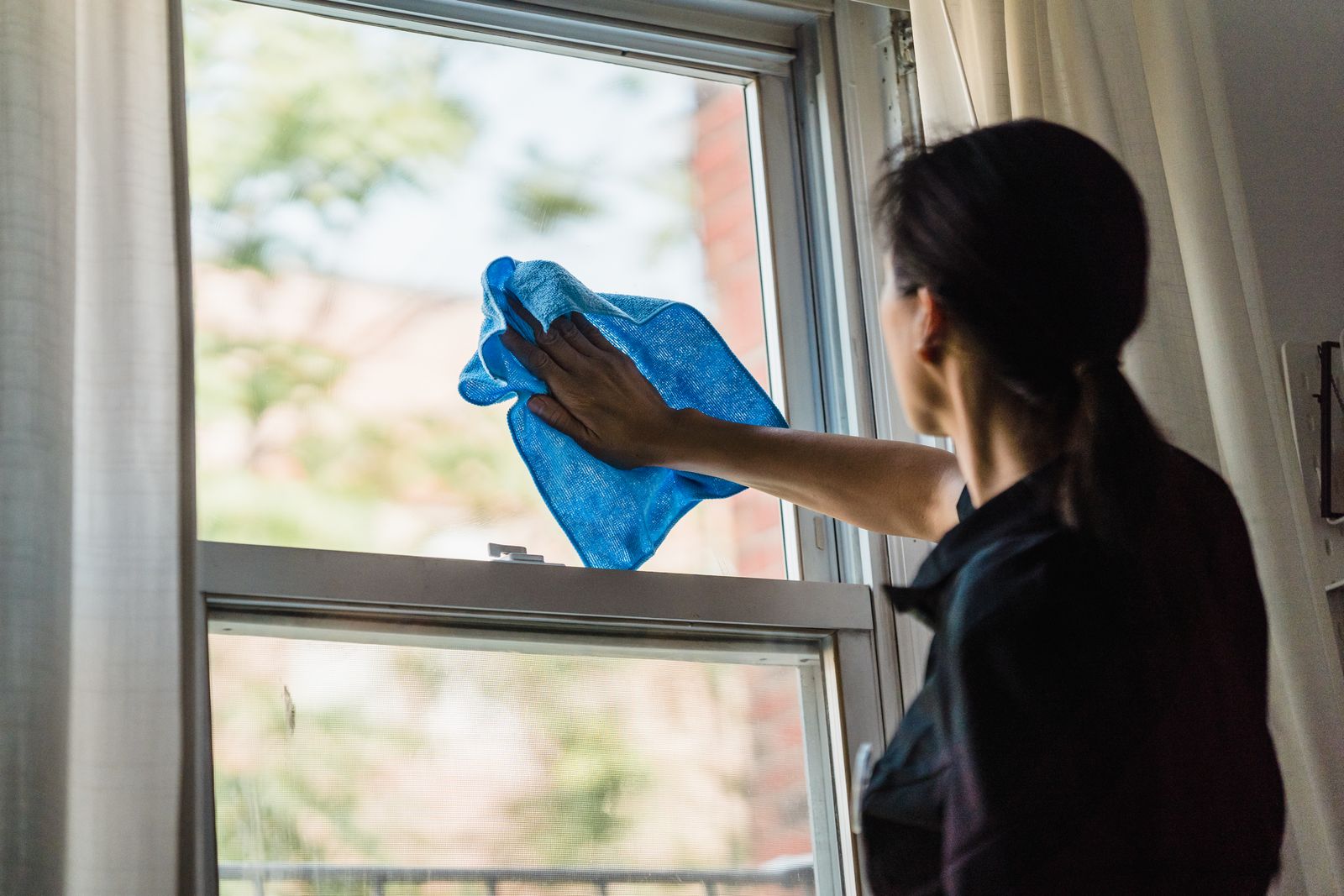 Window being cleaned with a blue microfibre cloth for a streak-free finish