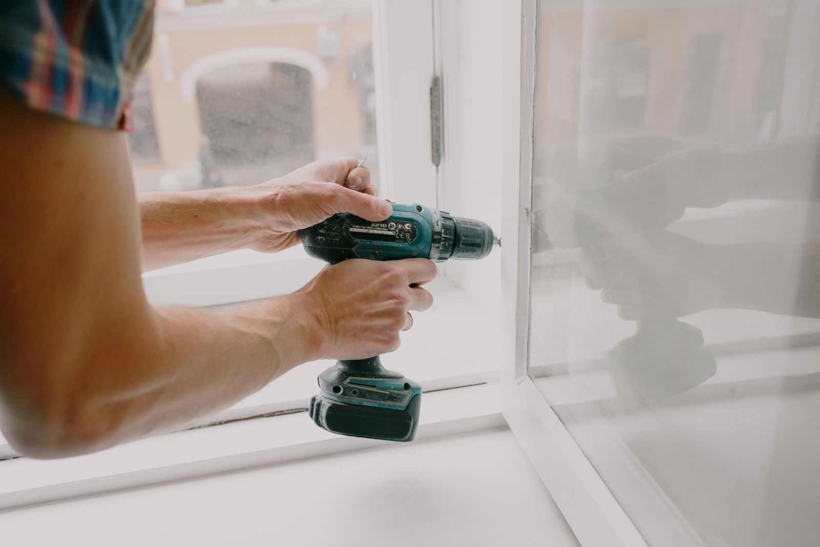 Technician tightening screws on a window frame