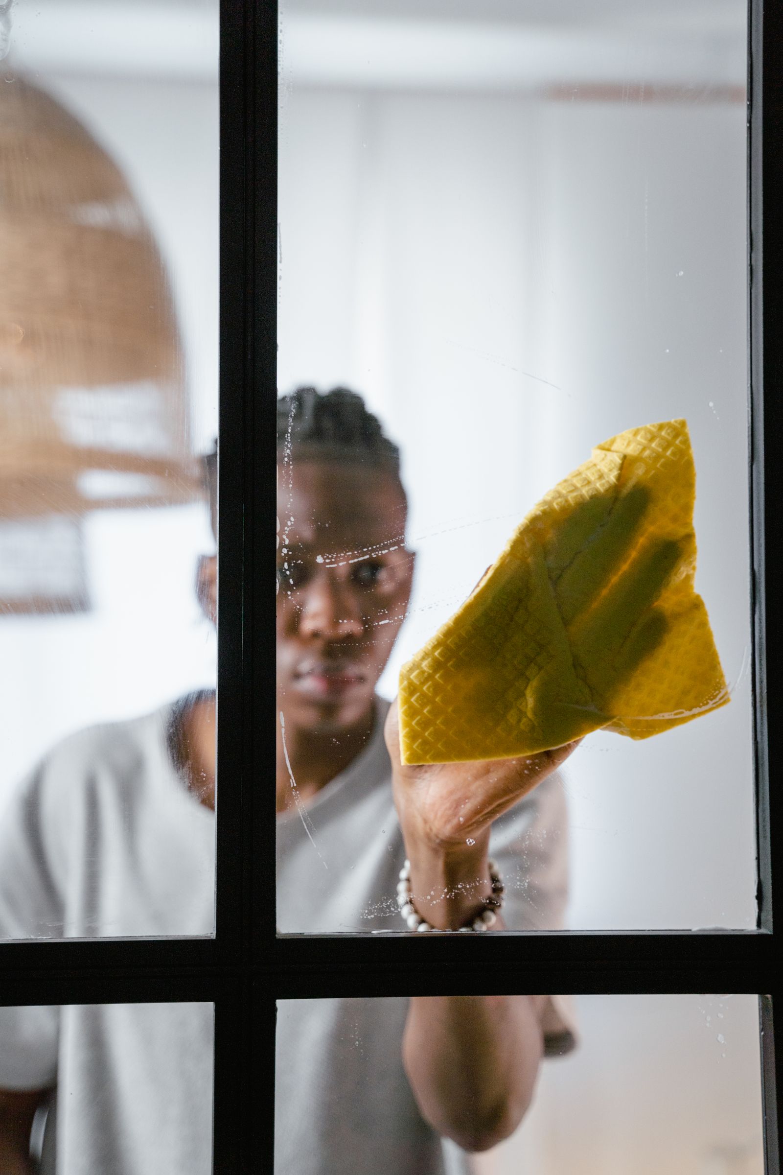 Technician wiping a glass window with a yellow microfibre cloth