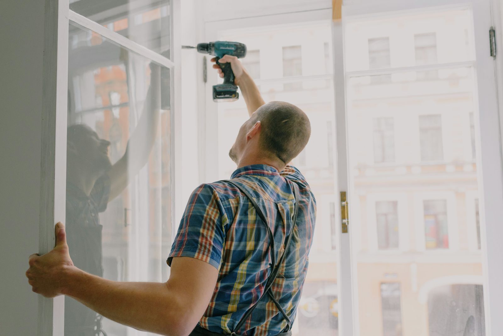 Installer securing a window frame with a power drill