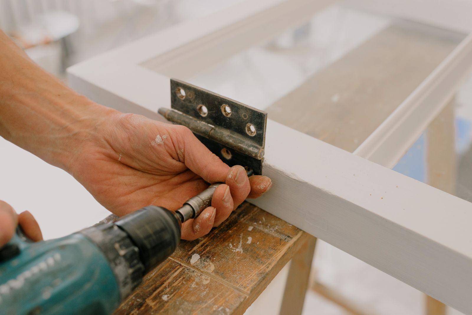 Technician drilling a new hinge into a window frame